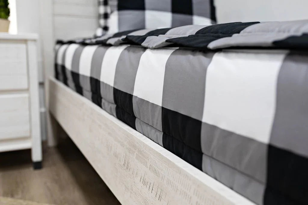 
      A low side shot of a bed made with black and white checked zipper bedding
    