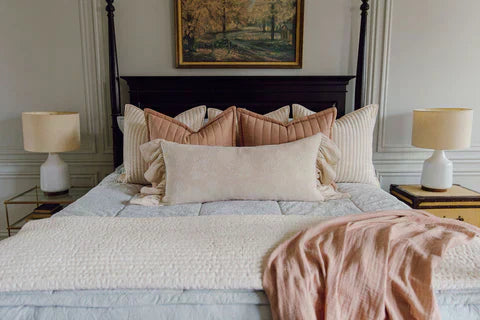 
      A bed in a primary bedroom made with light blue zipper bedding and an assortment of cream and terracotta bedding accessories.
    