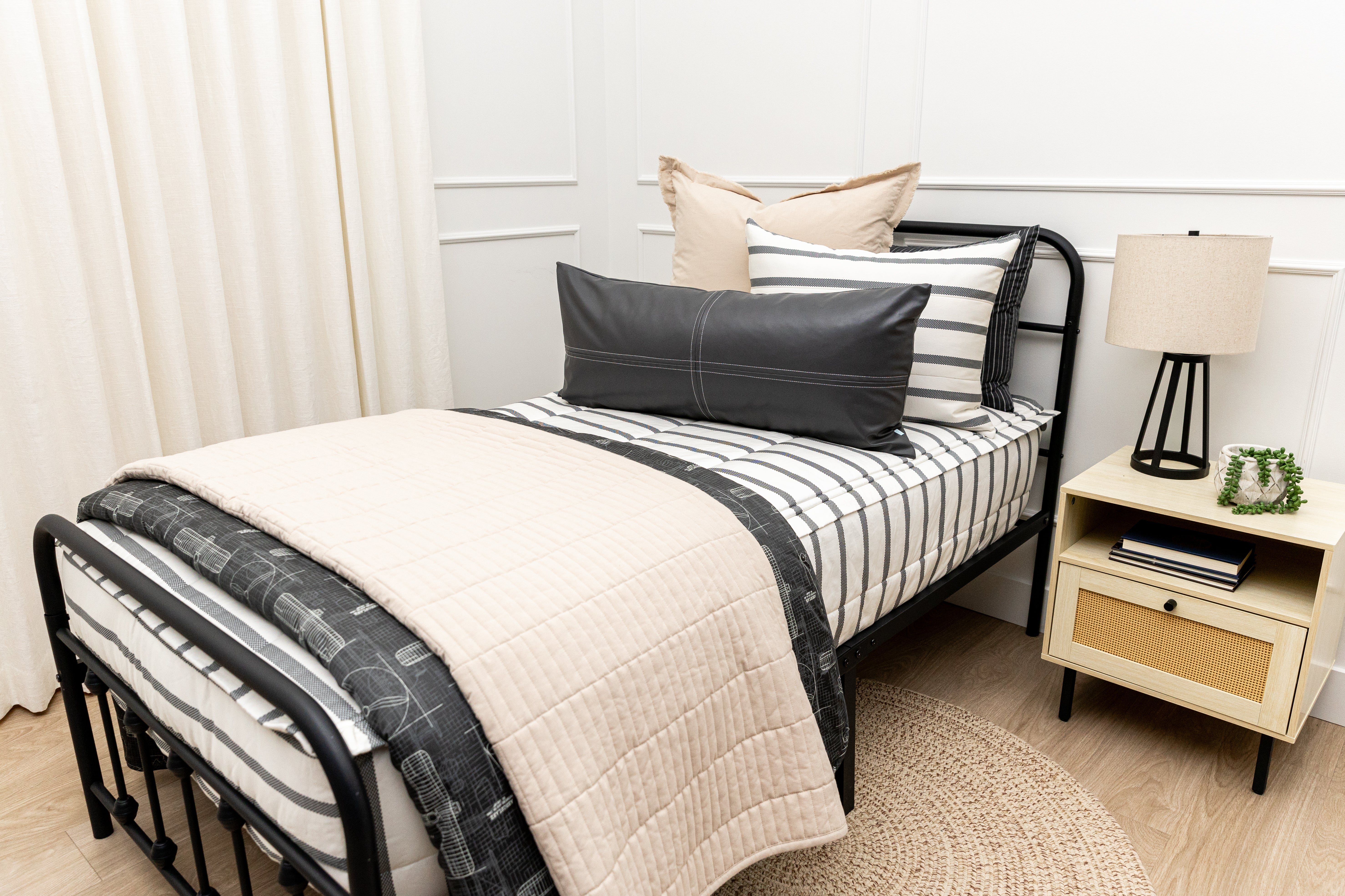 A queen bed made with white and black striped zipper bedding paired with neutral and black accessories.
