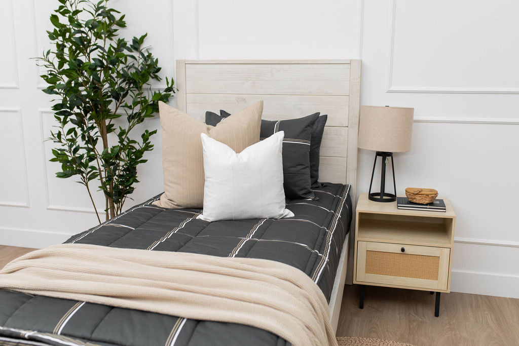 A queen bed made with black plaid zipper bedding and an assortment of neutral bedding accessories