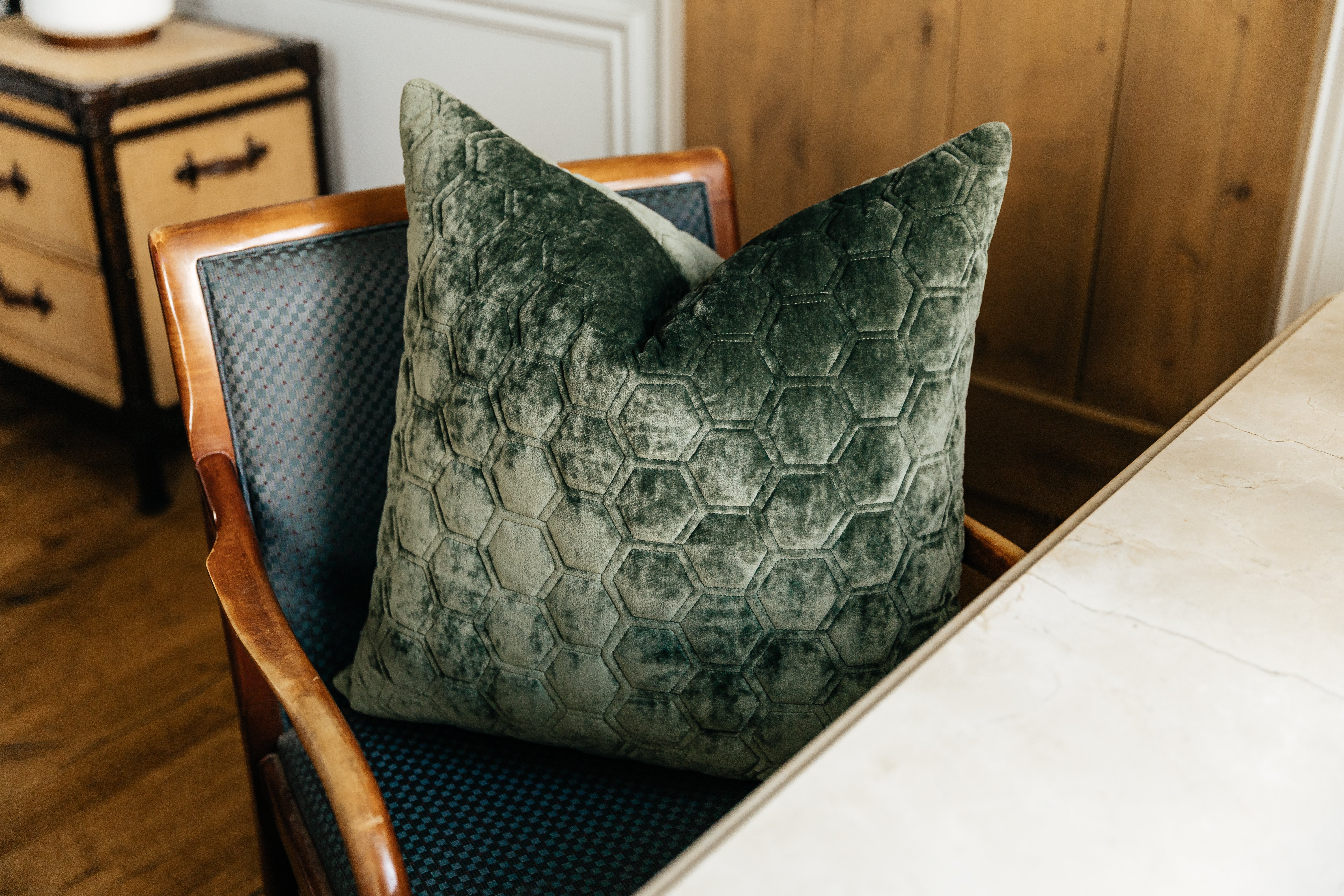 A green honeycomb pattern velvet euro pillow arranged on a chair next to a desk.