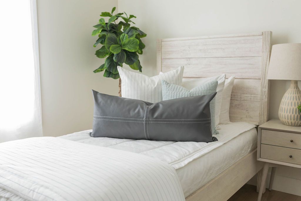 A bed made with white woven plaid zipper bedding and an assortment of neutral throw pillows and blanket.